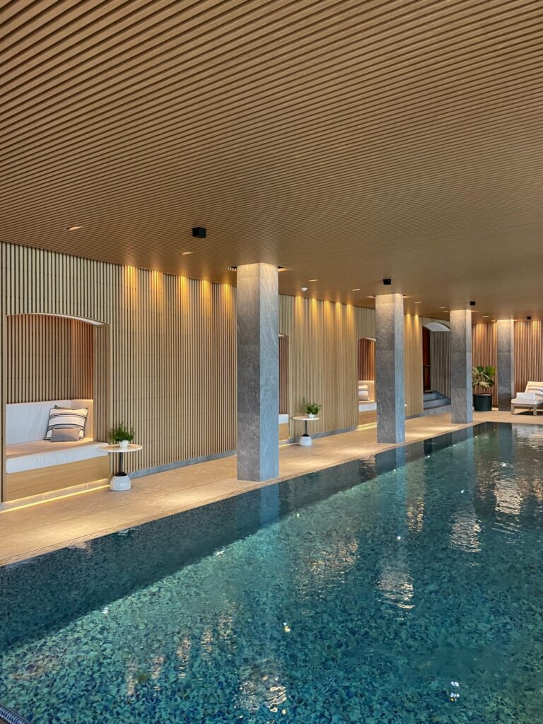 Beleuchteter Innenpool mit Mosaikboden und Holzdecke im Asaya Spa des Rosewood Schloss Fuschl