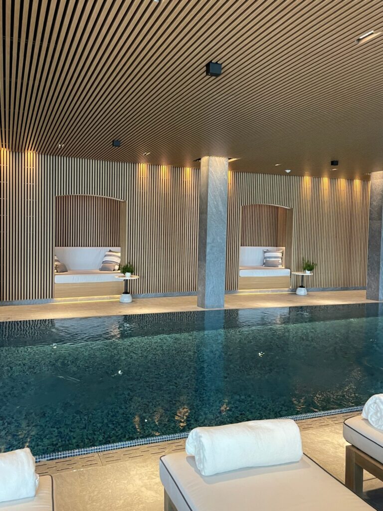Liegen mit weißen Handtüchern am beleuchteten Innenpool im Asaya Spa des Rosewood Schloss Fuschl