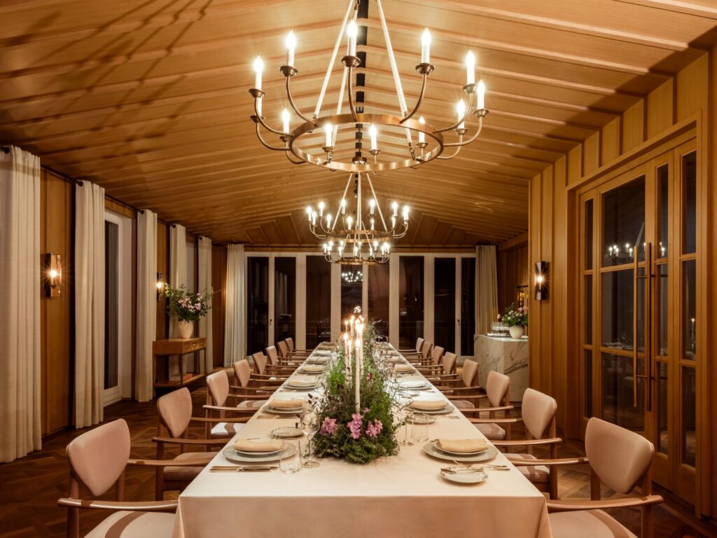 Lange Hochzeitstafel mit Blumenschmuck und Kronleuchtern im Glas Salon des Rosewood Schloss Fuschl