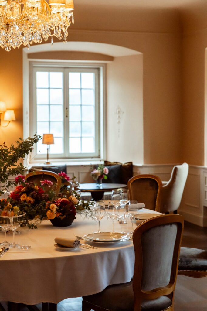 Festlich gedeckte runde Tafel mit Blumen im Rosa Salon für Feiern im engsten Familienkreis