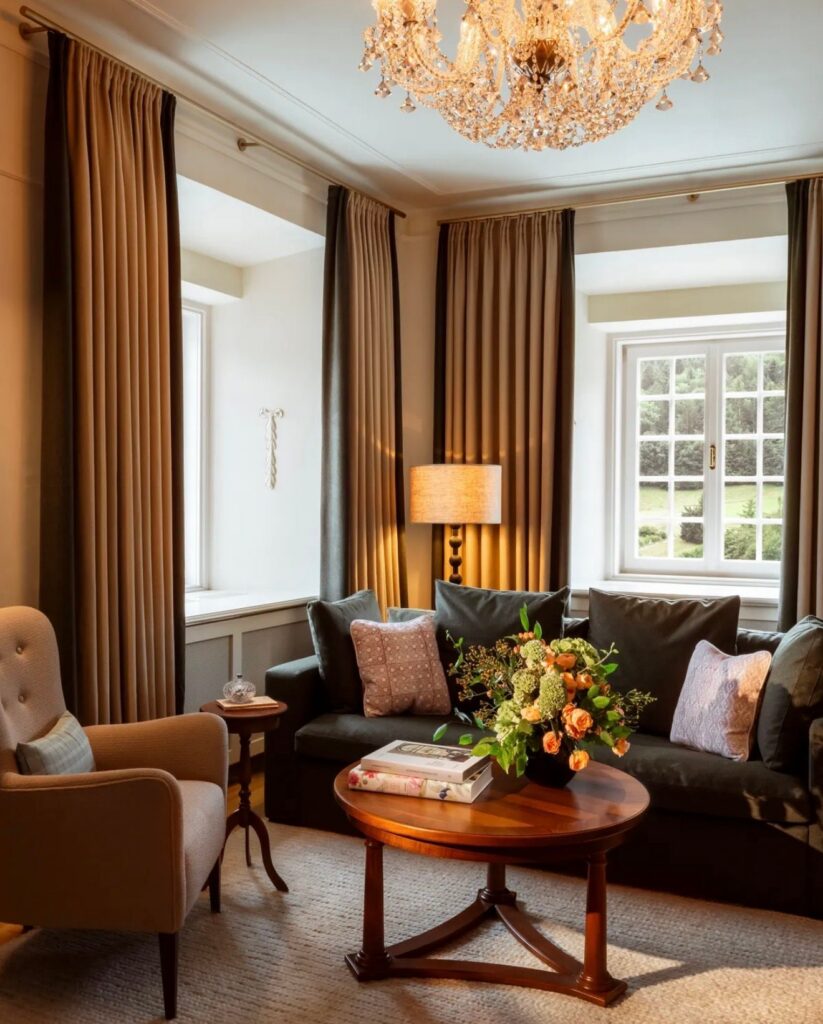 Gemütliche Sitzecke mit Sofa, Sessel und Blumenstrauß im Salon einer Suite am Fuschlsee