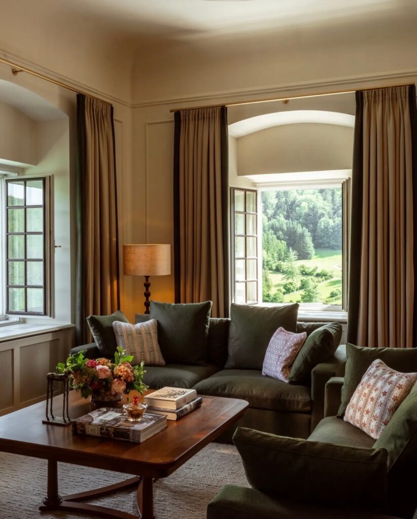Wohnbereich einer Suite mit grünem Sofa, Couchtisch und Blick ins Grüne im Rosewood Schloss Fuschl